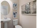 Stylish powder room with pedestal sink, oval mirror, artwork, and a sleek, modern toilet at 15 Camellia Dr, Fairburn, GA 30213