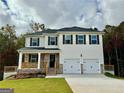 Two-story home boasts a covered front porch, two-car garage, and manicured lawn on a wooded lot at 748 Great Oak Pl, Villa Rica, GA 30180