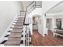 Bright entryway with hardwood floors, staircase, and view into the living room featuring a stone fireplace at 5015 Preservation Pointe Nw, Kennesaw, GA 30152