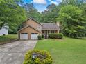 Charming two-story home featuring a well-manicured lawn, mature trees, and an attached two-car garage at 4896 Muirwood Dr, Powder Springs, GA 30127