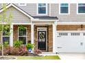 Close-up of front entrance featuring brick columns, a black door with a wreath, and manicured shrubs at 13568 Scenic Pkwy, Covington, GA 30014