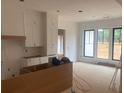 Unfinished kitchen with white cabinets, stainless appliances, and large windows overlooking the yard at 933 Mount Carmel Church Ln, Canton, GA 30114