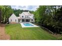 Aerial view of a backyard featuring a modern pool, green grass, and wooded surroundings at 541 Londonberry Rd, Atlanta, GA 30327