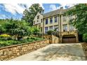 Spacious home featuring a stone retaining wall, lush landscaping, and a gated drive-under garage at 171 Beverly Ne Rd, Atlanta, GA 30309