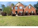 Beautiful two-story brick home featuring a lush green lawn and manicured shrubbery at 1905 Buford Ct, Conyers, GA 30094