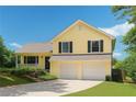 Inviting yellow home featuring a two-car garage, well-kept lawn, and a charming front porch, creating a welcoming curb appeal at 309 Carmen Ct, Lawrenceville, GA 30046