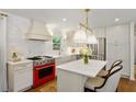Bright kitchen featuring white cabinets, a red range, an island with marble countertop and pendant lighting at 3872 Francis Dr, Powder Springs, GA 30127