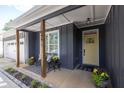 Inviting covered porch features seating, a yellow front door, dark gray siding, and manicured landscaping at 399 Chestnut St, Social Circle, GA 30025