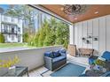 Relaxing covered patio with comfortable seating, wood ceiling and fan, overlooking lush greenery at 212 Sessions St, Woodstock, GA 30188