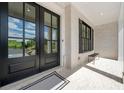 Close-up of the front door and entry featuring large black framed windows, a brick base, and a welcome mat at 17145 River Overlook Dr, Roswell, GA 30075