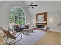 Spacious living room with a soaring arched window, fireplace with brick accent, and a cozy seating area at 6030 Sweet Creek Rd, Duluth, GA 30097