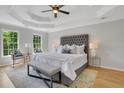 Serene main bedroom features a tray ceiling, hardwood floors, a plush bed, and abundant natural light at 6030 Sweet Creek Rd, Duluth, GA 30097