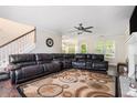 Inviting living room features a large leather sectional sofa, fireplace, ceiling fan, and stylish area rug at 3885 Weeping Willow Ln, Loganville, GA 30052