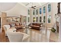 Bright living room boasts soaring ceilings, hardwood floors, fireplace, and many tall windows at 3456 Glen Mist Pl, Dacula, GA 30019