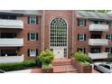 Brick condo building with large arched window, manicured landscaping, and covered balconies provides inviting curb appeal at 107 Ridley Howard Ct, Decatur, GA 30030