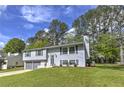 Gray split-level home with a two-car garage, lush lawn, and well-maintained landscaping at 1460 Parkmont Dr, Roswell, GA 30076