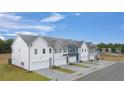 Street view of new townhomes boasting varied colors, attached garages and neatly manicured lawns on a sunny day at 54 Leggett Dr, Villa Rica, GA 30180