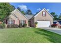 Lovely brick home featuring a well-manicured lawn and a two-car garage and bright yellow front door at 755 James Ridge Dr, Lawrenceville, GA 30045