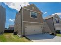 Side angle of two-story home featuring gray siding, green grass, and a two car garage at 109 Auburn Crossing Dr, Auburn, GA 30011