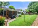 Spacious backyard with a screened-in porch, lush green lawn, and beautiful landscaping features at 503 Bonnie Dr, Woodstock, GA 30188