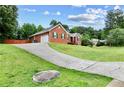 View of a sloped driveway leading to a brick home with an attached garage, set among lush greenery at 124 Crown Walk, Mcdonough, GA 30253