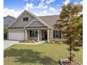 Beautifully landscaped front yard with a well-maintained lawn, and a brick and shingle home with an attached garage at 7995 Brewton Creek Dr, Cumming, GA 30028
