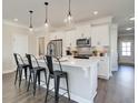 Bright kitchen with pendant lights over the island with white cabinets, stainless appliances, and grey backsplash at 4527 Moray Dr, Mableton, GA 30126