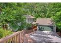 Home exterior featuring a two-car garage with green door, wooden walkway, and surrounded by mature trees at 615 Nw Mark Trail Nw Ct, Atlanta, GA 30328