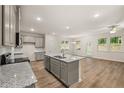 Modern kitchen with stainless appliances, granite countertops, island, and wood-look floors at 9457 Briarwood Ln, Jonesboro, GA 30238