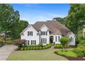 Elegant home with a manicured lawn, shrubbery, and a circular driveway, exuding curb appeal at 9115 Nesbit Lakes Dr, Alpharetta, GA 30022
