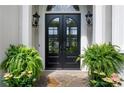 Elegant arched double front doors with decorative lanterns and lush ferns enhance the home's entry at 9115 Nesbit Lakes Dr, Alpharetta, GA 30022