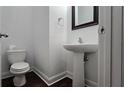 Half bathroom featuring a pedestal sink, toilet, modern mirror, and dark wood-like flooring at 2275 Copper Trail Ln, Buford, GA 30519