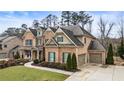 Brick home featuring a well-manicured lawn, a two-car garage, and mature trees at 4120 Winterberry Rd, Cumming, GA 30040