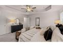 Relaxing main bedroom featuring a ceiling fan, a tray ceiling, and a dresser with a round mirror at 1031 Merritt Dr # 96, Villa Rica, GA 30180