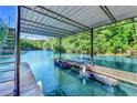 Covered dock with boat slips and ladders overlooking blue water surrounded by a lush, green forest at 975 Timber Lake Trl, Cumming, GA 30041