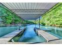 Covered dock showing boat slips with ladders and a metal roof, surrounded by trees at 975 Timber Lake Trl, Cumming, GA 30041