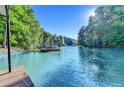 A scenic lake view showing a dock with a covered sundeck surrounded by green trees at 975 Timber Lake Trl, Cumming, GA 30041