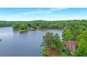 Scenic aerial view of a house nestled by a serene lake surrounded by dense forest at 160 Old Mill Ct, Fayetteville, GA 30214
