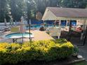 Community pool area featuring a jacuzzi, sun umbrellas, chairs, and a covered lounge at 1690 Cedar Grove Dr, Marietta, GA 30066