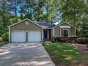 Charming single-story home with a two-car garage and blue front door framed by mature trees and green grass at 2160 Towne Manor Nw Dr, Kennesaw, GA 30144
