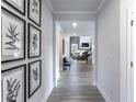 Inviting home hallway featuring wood-look flooring, neutral paint, decorative wall art, and an open view to the living area at 5121 Hillside Haven Drive, Powder Springs, GA 30127