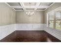 Formal dining room featuring elegant chandelier, coffered ceiling, and wainscoting at 4910 Bucknell Trce, Cumming, GA 30028