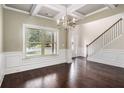 Formal dining room open to the entry featuring elegant chandelier, coffered ceiling, and wainscoting at 4910 Bucknell Trce, Cumming, GA 30028