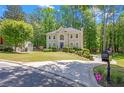 Beautifully landscaped two-story home with a circular driveway and a well-maintained lawn at 222 Mossy Pl, Alpharetta, GA 30005
