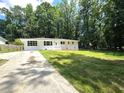 A charming white brick ranch-style home with a lush green front lawn, surrounded by mature trees at 345 Forest Valley Rd, Lawrenceville, GA 30046