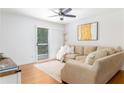 Cozy living room featuring a comfortable beige sofa, ceiling fan, and sliding door to a balcony at 6204 Santa Fe Pkwy, Atlanta, GA 30350