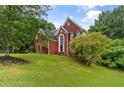 A stately brick home on a well-manicured lawn featuring mature trees at 3014 Volland Grove Trail, Lawrenceville, GA 30043