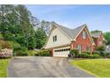 Side view of a brick home with a two-car garage and well-kept landscaping at 9545 Kingston Crossing Cir, Alpharetta, GA 30022