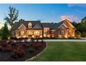 Elegant brick and stone home at dusk, showcasing landscape lighting and a circular driveway at 341 Carl Sanders Dr, Acworth, GA 30101