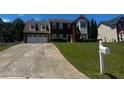 Charming two-story brick home with attached two car garage, manicured lawn, and long driveway at 8529 Glendevon Ct, Riverdale, GA 30274